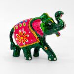 Brighten your home with this stunning colorful elephant decor set, featuring a pack of 2 handcrafted, hand-painted elephant figurines. Made in the traditional Rajasthani folk art style, each elephant is painted in a rich green tone with decorative pink ears, floral saddles in bright red-orange, and intricate white and yellow accents. At 3 inches tall and 4 inches long, these miniatures are ideal for decorating living rooms, puja corners, festive centerpieces, or cultural gift hampers. Elephants are cherished in Indian tradition as symbols of power, protection, and prosperity, and this pair captures that essence beautifully. Weighing 98g together, this set is lightweight yet visually impactful.